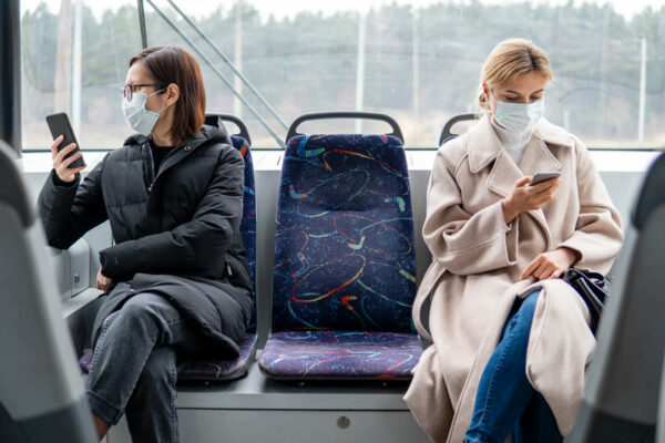 Persoane cu mască chirurgicală călătorind în mijloc de transport în comun.